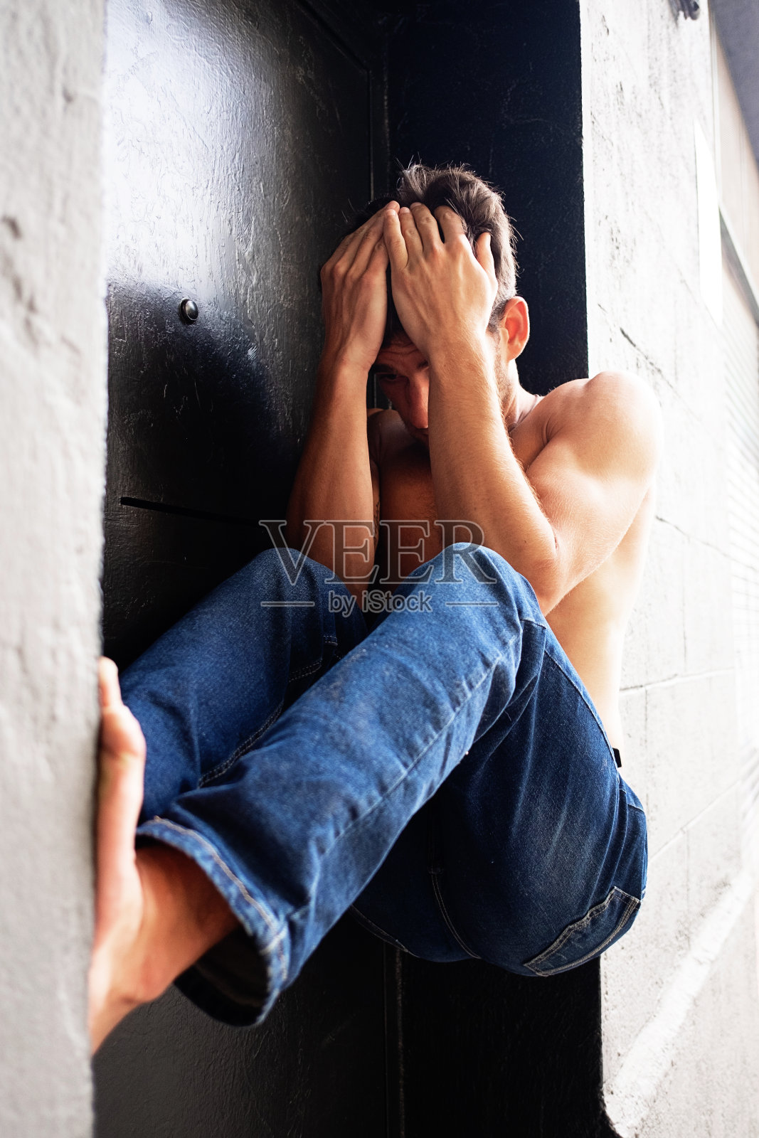 赤裸的年轻人坐在户外焦急的双手顶在头上照片摄影图片