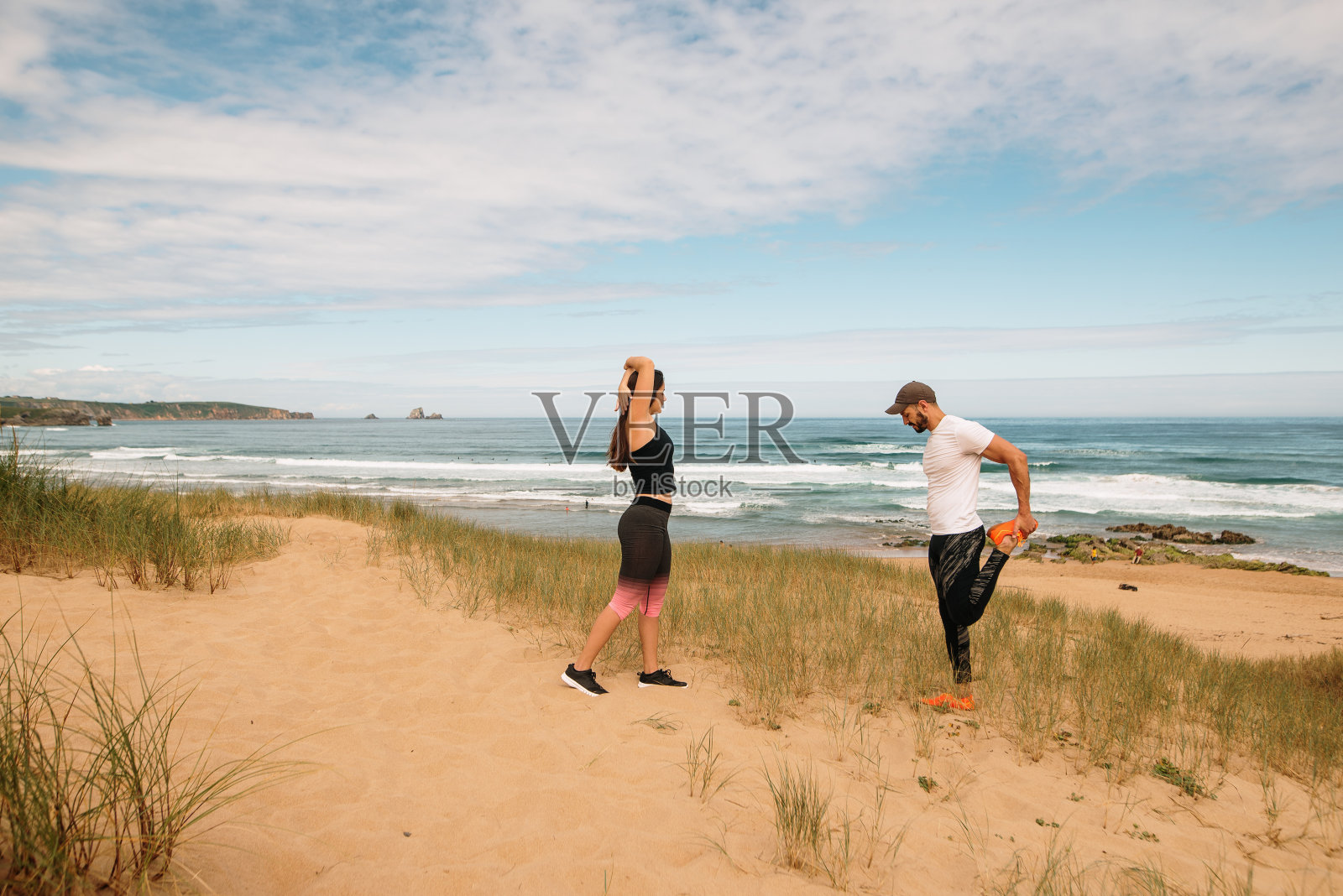 一对年轻夫妇在海滩上舒展身体照片摄影图片