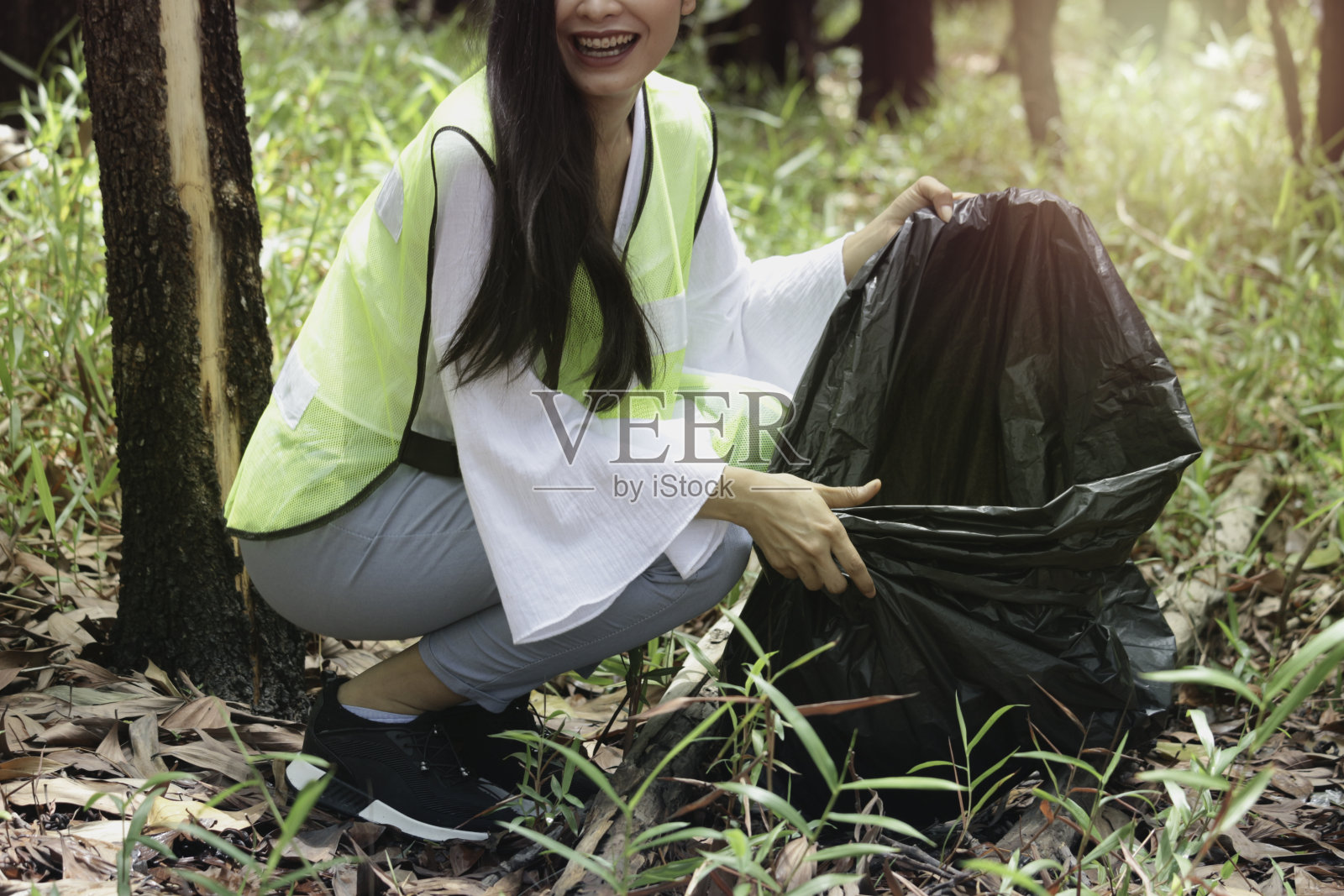年轻美丽的女子志愿者收集垃圾垃圾，拿着黑色垃圾袋，清理肮脏的区域，环保慈善理念照片摄影图片