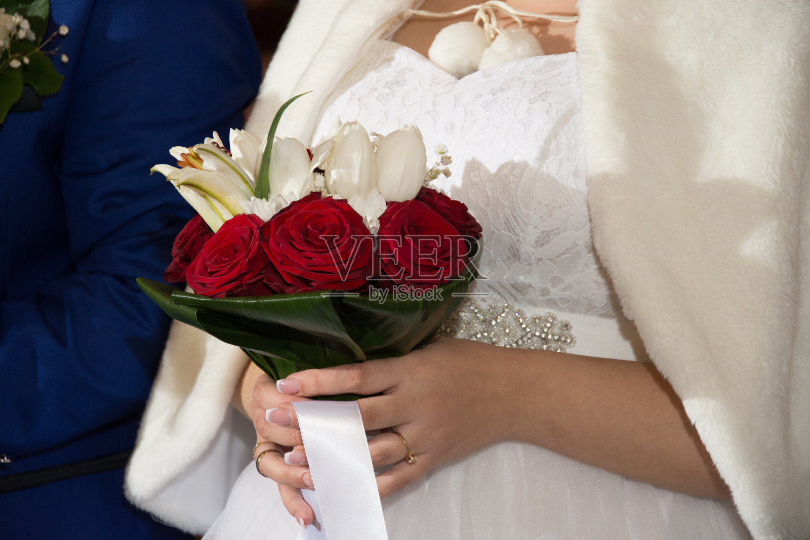 新娘身着白色婚纱，手捧一束红玫瑰照片摄影图片