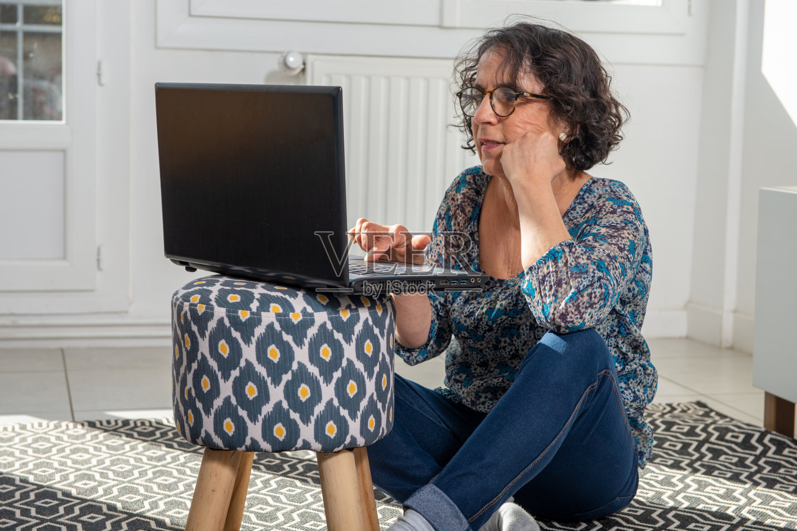 一个漂亮的黑发成熟女人的肖像，家里有一台笔记本电脑。照片摄影图片