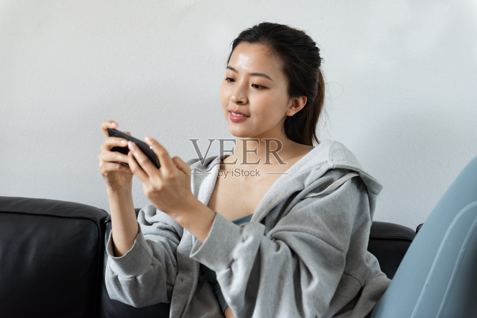 一位年轻的亚洲妇女在客厅里使用手机照片摄影图片