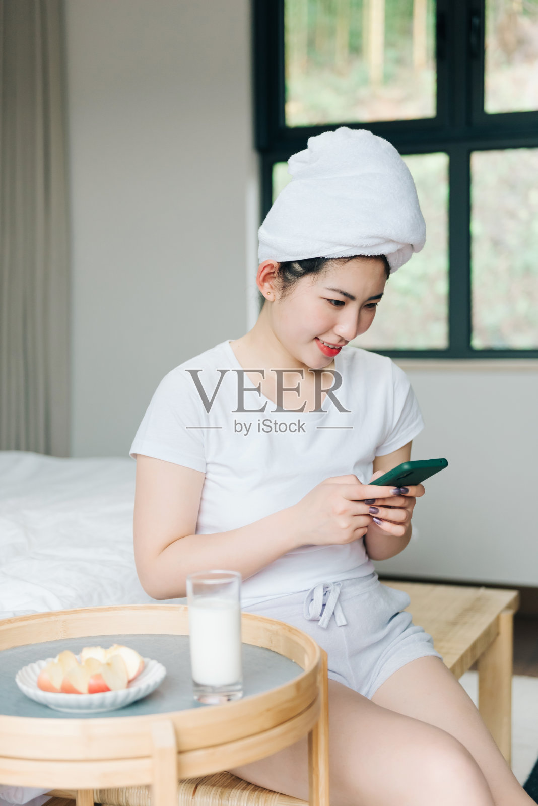 年轻的亚洲女孩在床上使用手机照片摄影图片