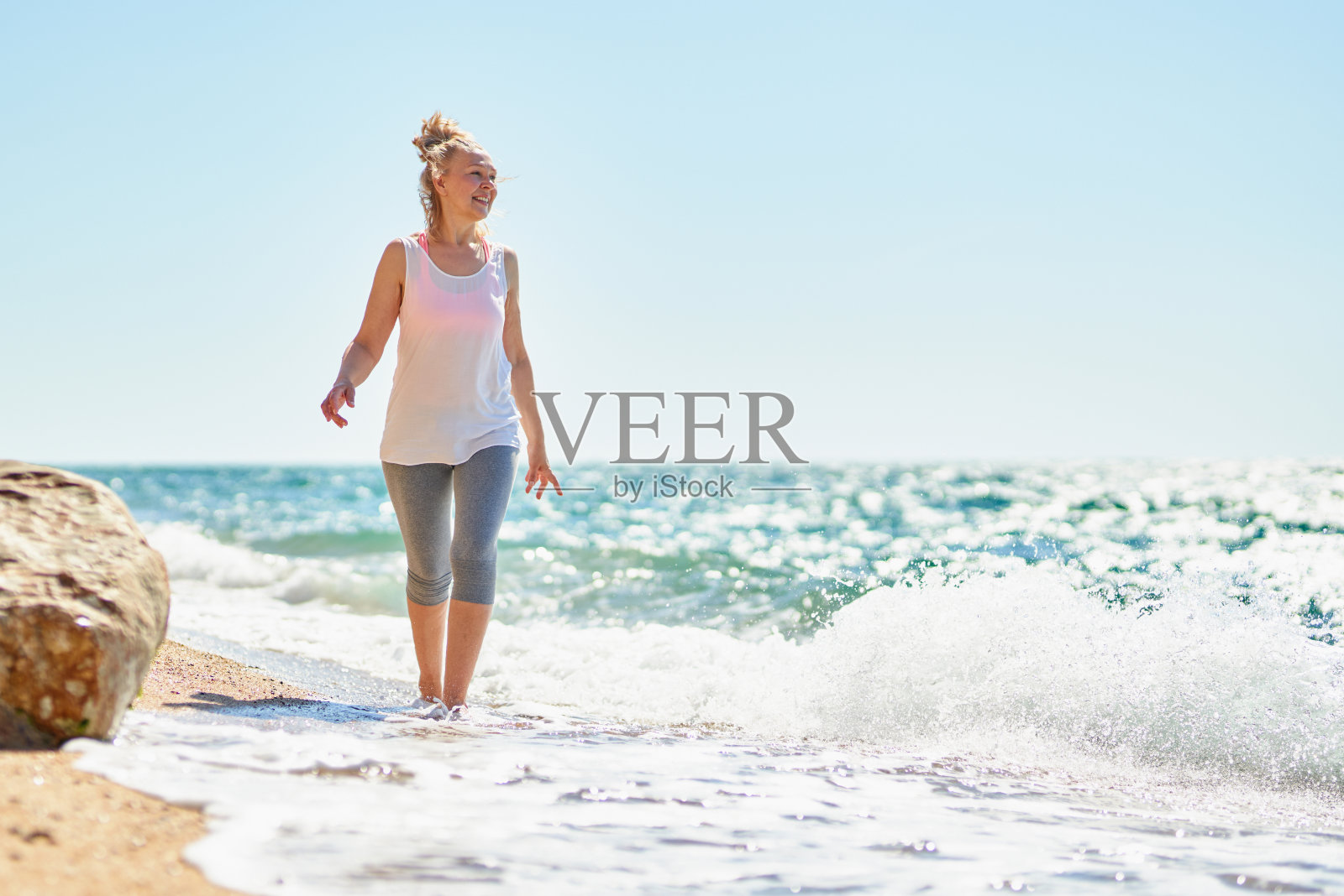 快乐的老妇人在海边散步。照片摄影图片