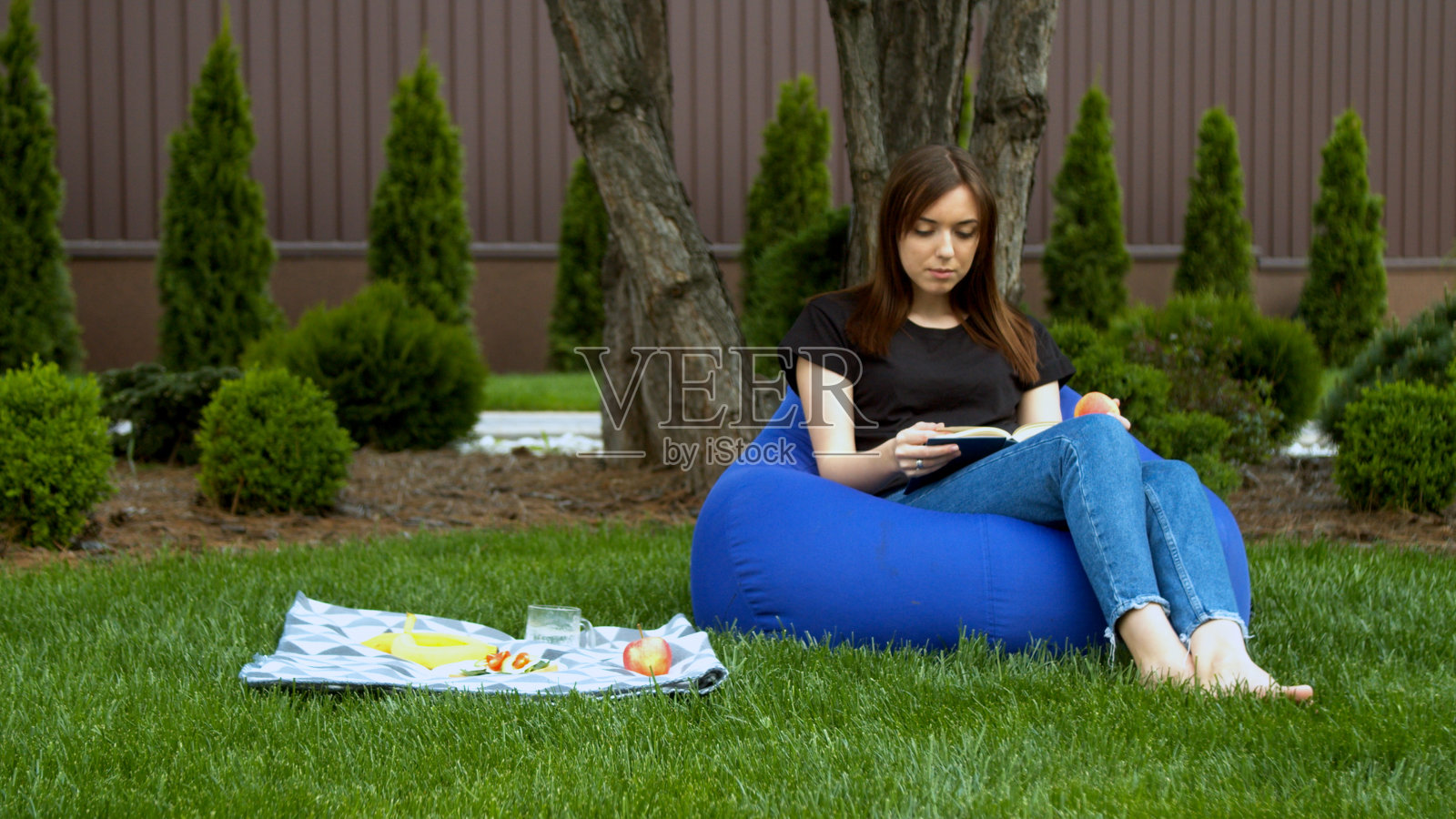 年轻女子在花园里看书照片摄影图片