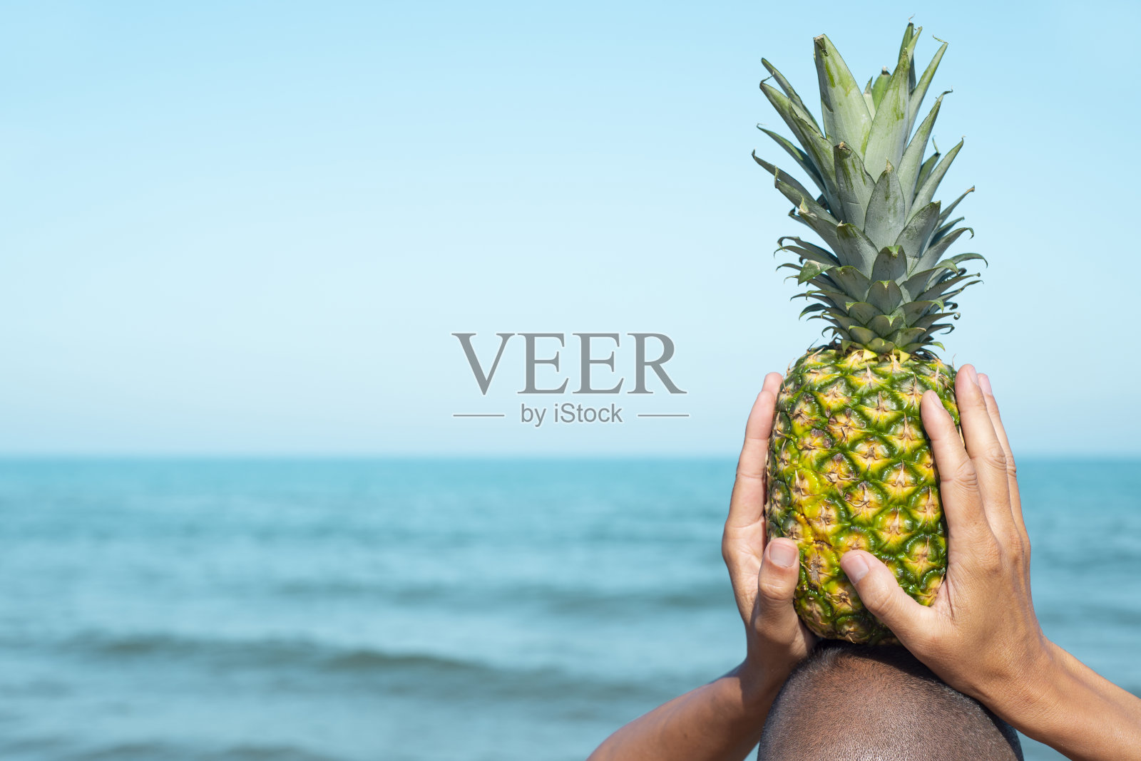 头上有个菠萝的男人照片摄影图片