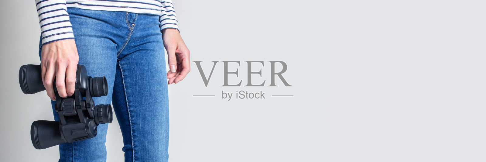 一个女人拿着双筒望远镜，背景很亮。只能看到腿。横幅照片摄影图片