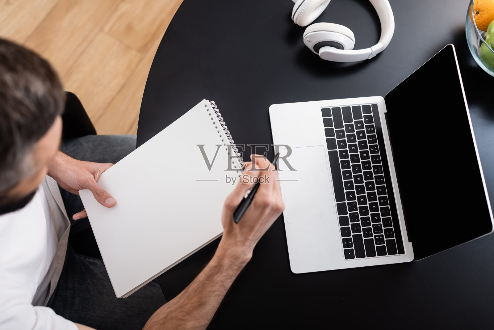 头顶上的自由职业者拿着笔记本电脑靠近笔记本电脑和耳机在桌子上照片摄影图片