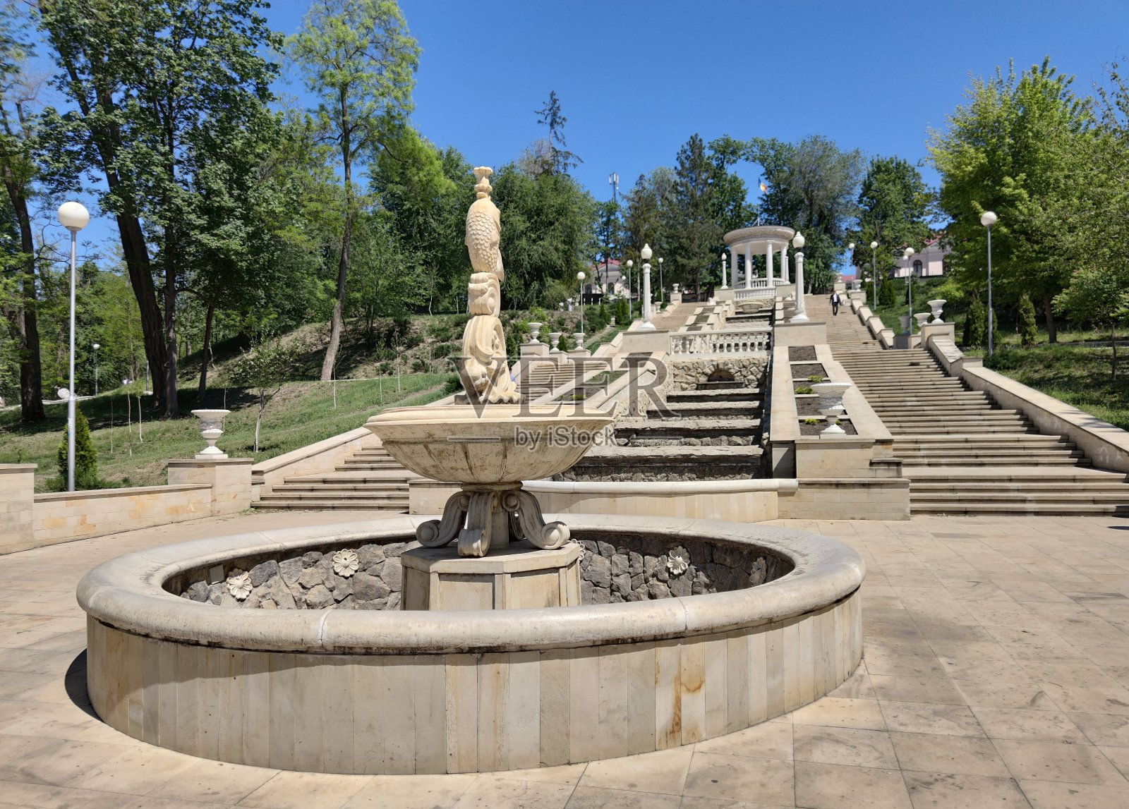 一个古老公园里的石头楼梯。绿色的树木。白色的石头。用于喷泉的水池照片摄影图片