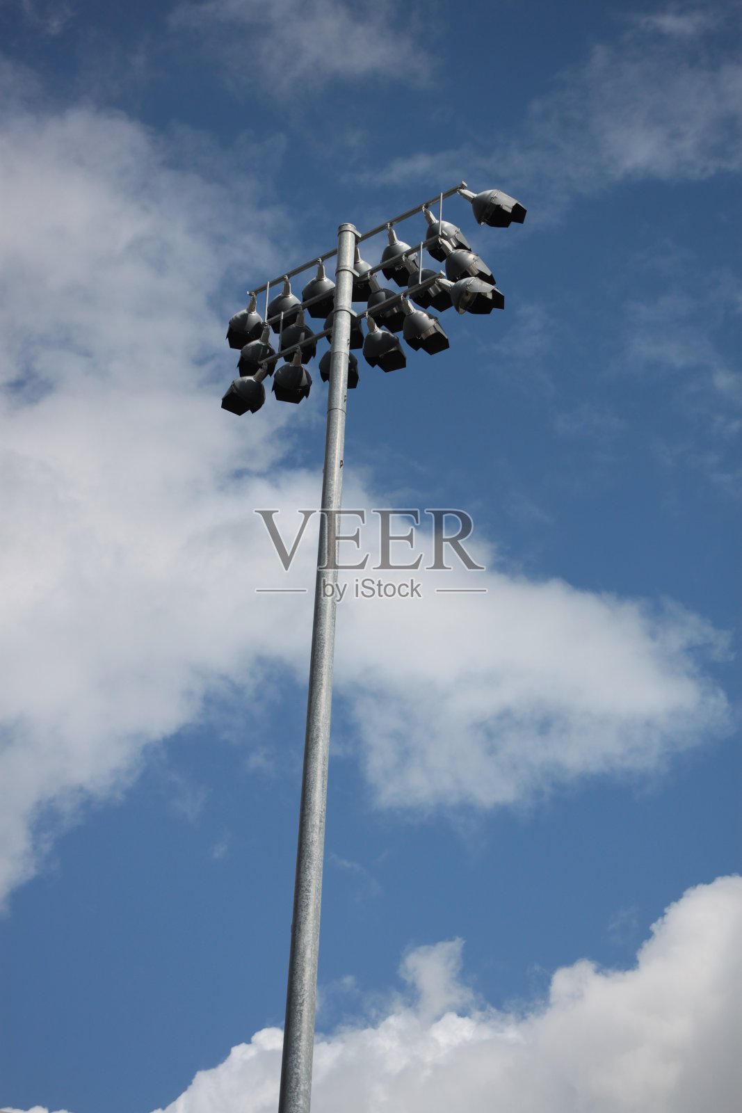 体育场的灯光在高高的柱子上，映衬着蓝天和白云照片摄影图片