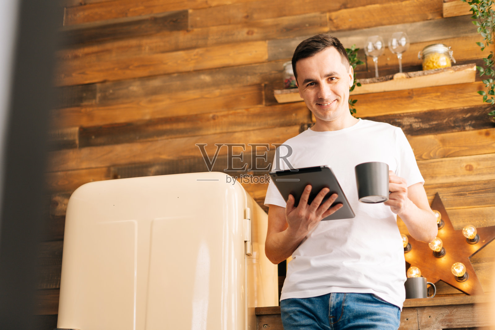 帅气的年轻人穿着休闲，拿着平板电脑，喝着咖啡照片摄影图片