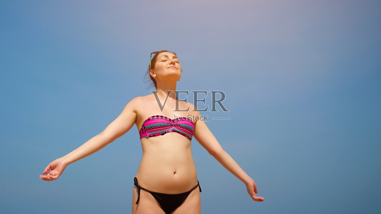 放松的女人站在海滩上晒太阳对着天空照片摄影图片