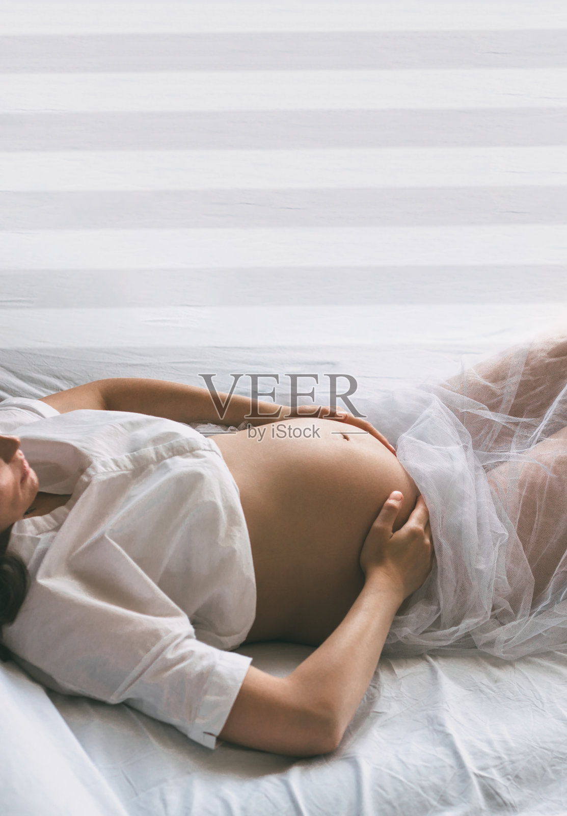 一名孕妇躺在床上，腹部露在外面照片摄影图片