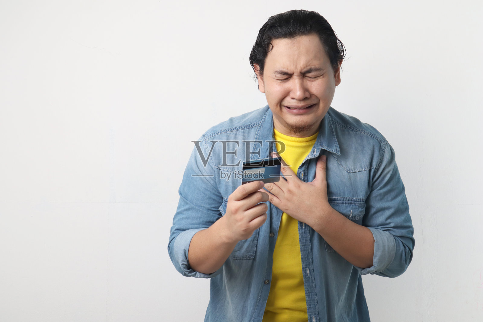 拿着信用卡哭的年轻人。破产的概念照片摄影图片