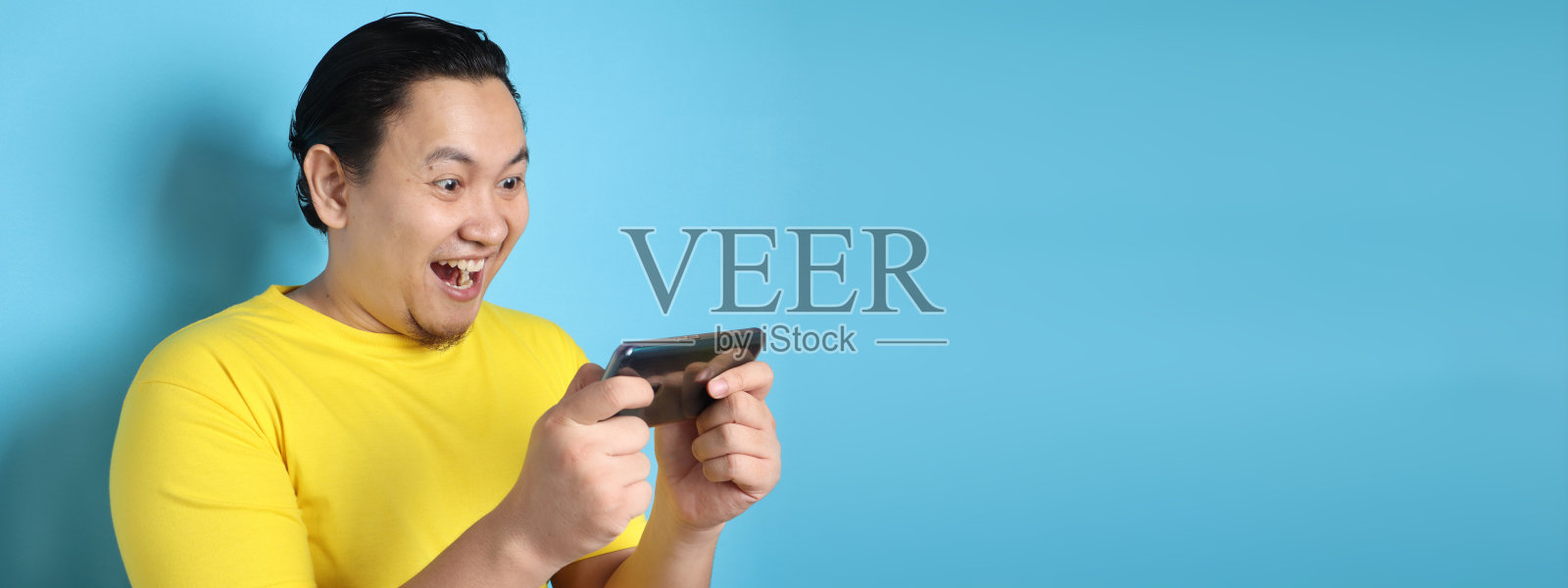 有趣的年轻亚洲人在平板智能手机上玩游戏照片摄影图片