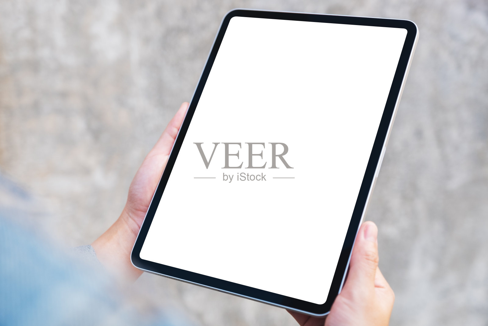 在户外的街道背景中，一个女人拿着一个黑色的平板电脑，屏幕是空白的照片摄影图片