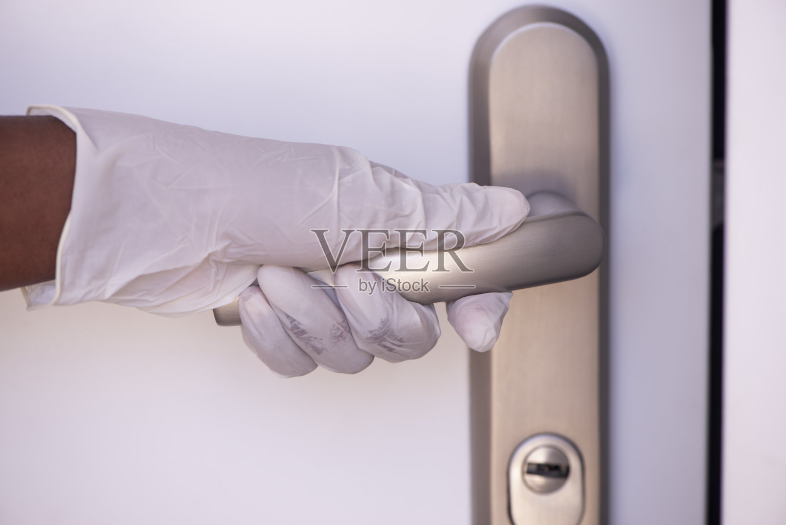 戴着外科手套的女性触摸金属门把手照片摄影图片
