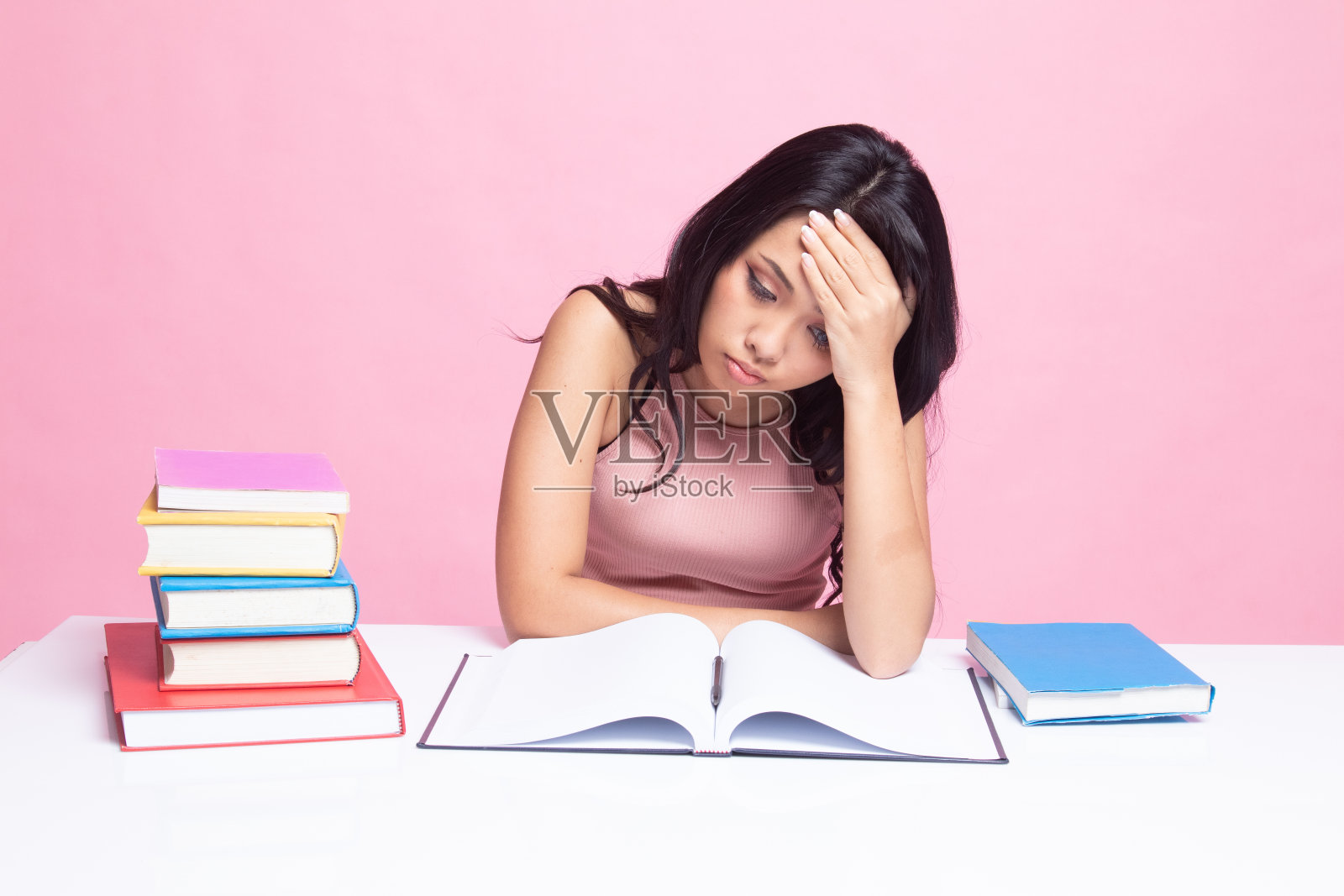 一位年轻的亚洲妇女在桌上看书。照片摄影图片