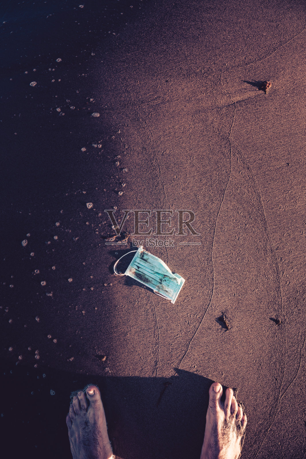 一个面具在海滩上的概念风景在一个人的脚前。检疫完成照片摄影图片