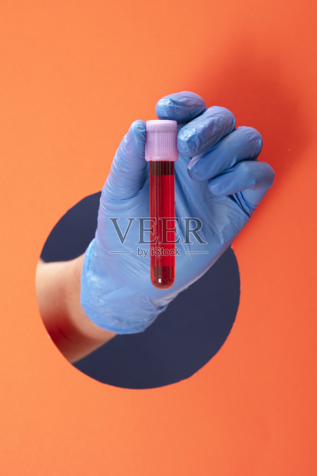 手握手术口罩，橙色背景。照片摄影图片