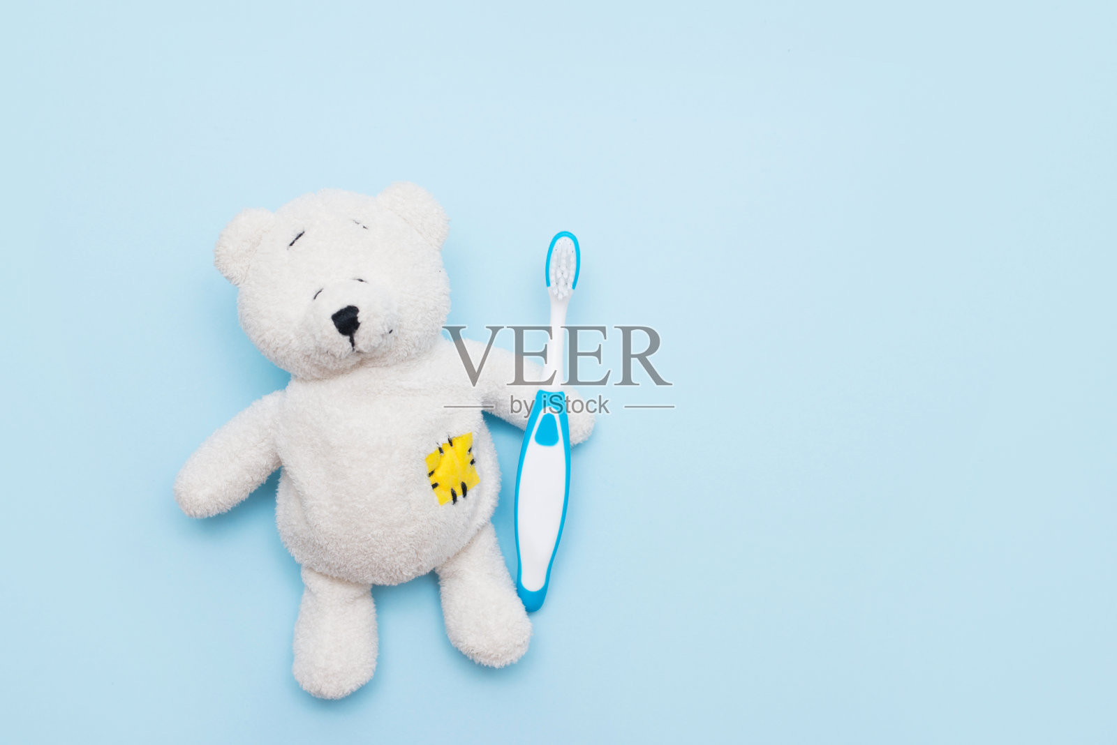 白色泰迪熊与牙刷在蓝色背景，复制空间照片摄影图片