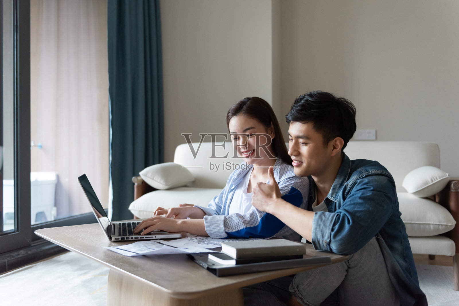 一对年轻的亚洲夫妇正坐在地毯上使用电脑照片摄影图片