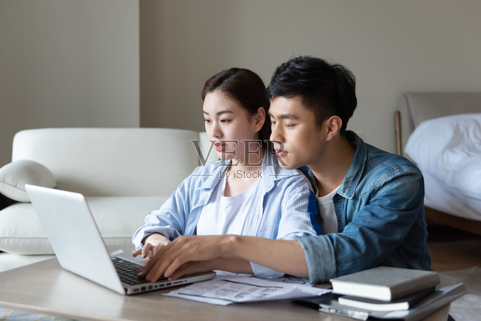 一对年轻的亚洲夫妇正坐在地毯上使用电脑照片摄影图片