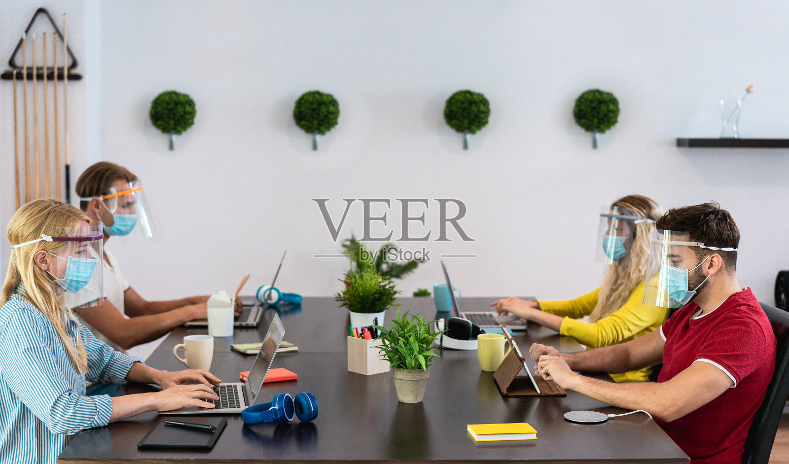 在共同工作创意办公室工作的年轻人，戴着预防冠状病毒传播的防护口罩——社交距离、科技和创业理念——关注左女性脸照片摄影图片