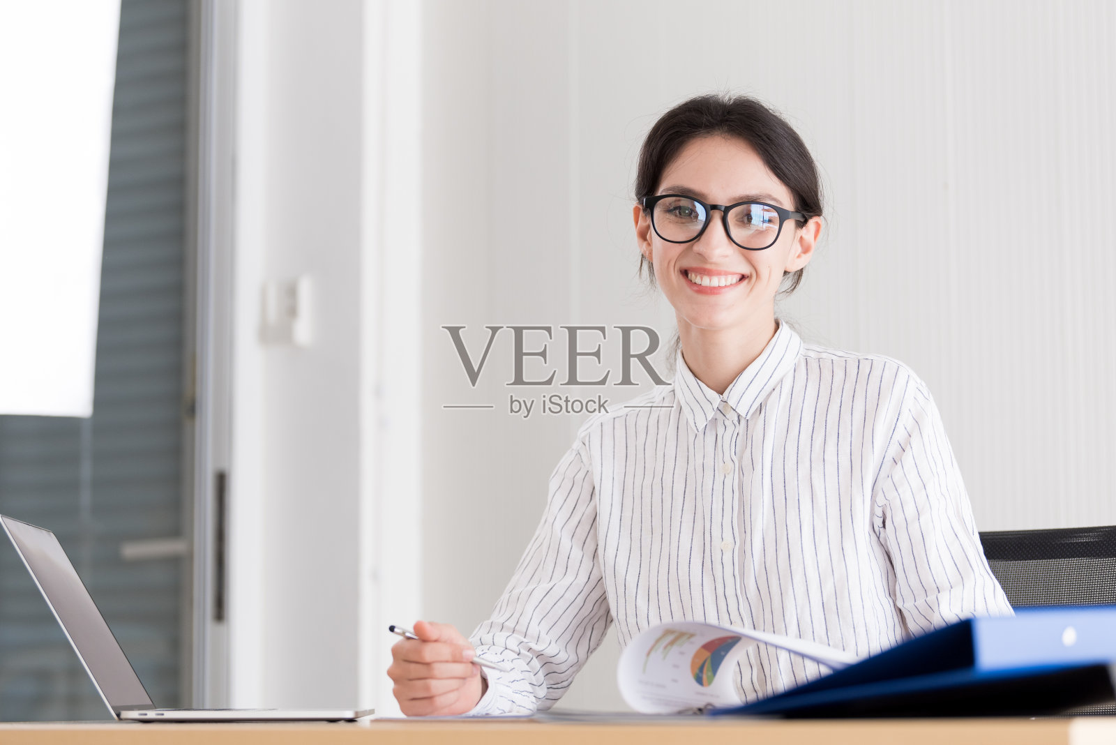 一个女商人戴着眼镜在办公室微笑和快乐地工作。照片摄影图片