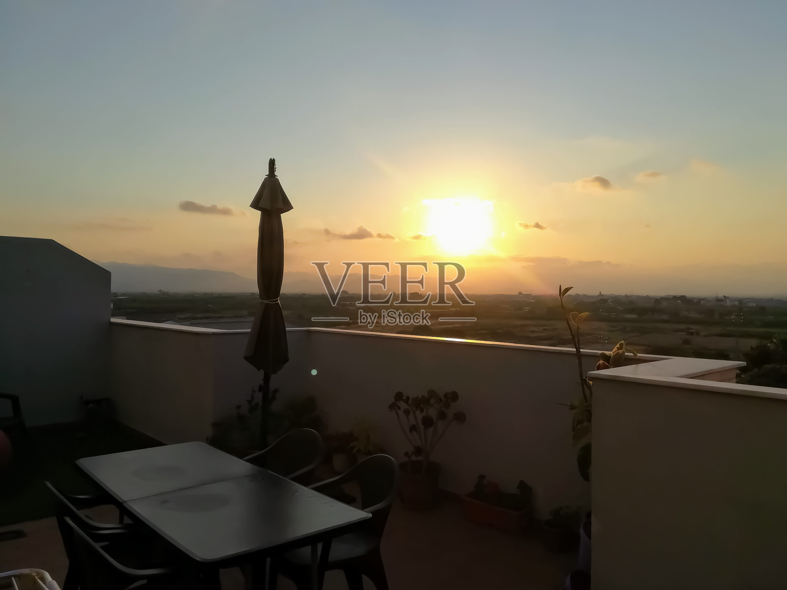 从阳台上打阳伞看山上的日落照片摄影图片