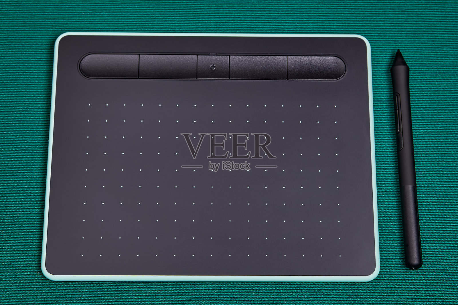 在绿色背景上使用手写笔的平板电脑。照片摄影图片