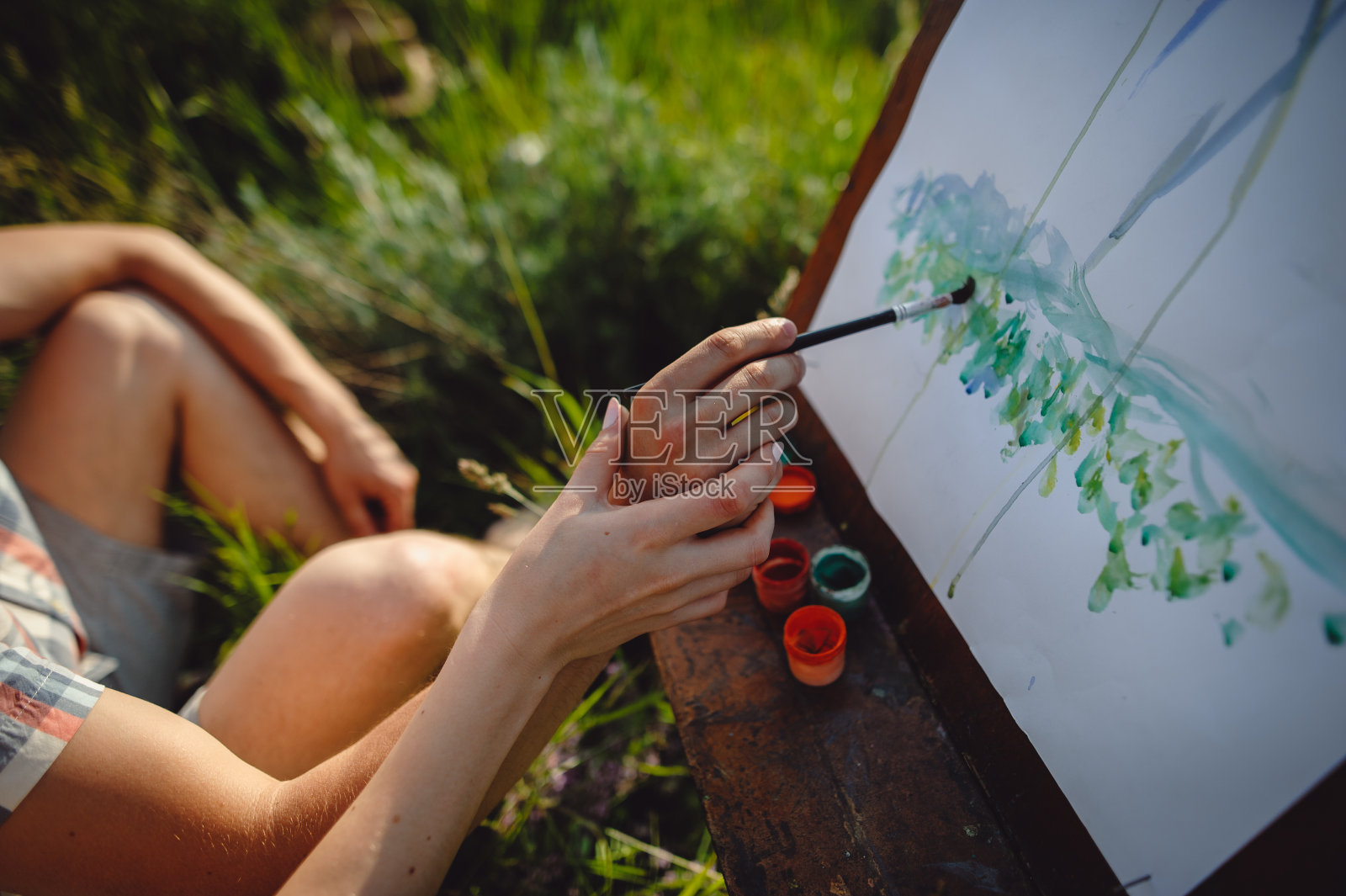 一对在城外度假的可爱艺术家夫妇。爱情故事。手在画架上用画笔画画，照片摄影图片