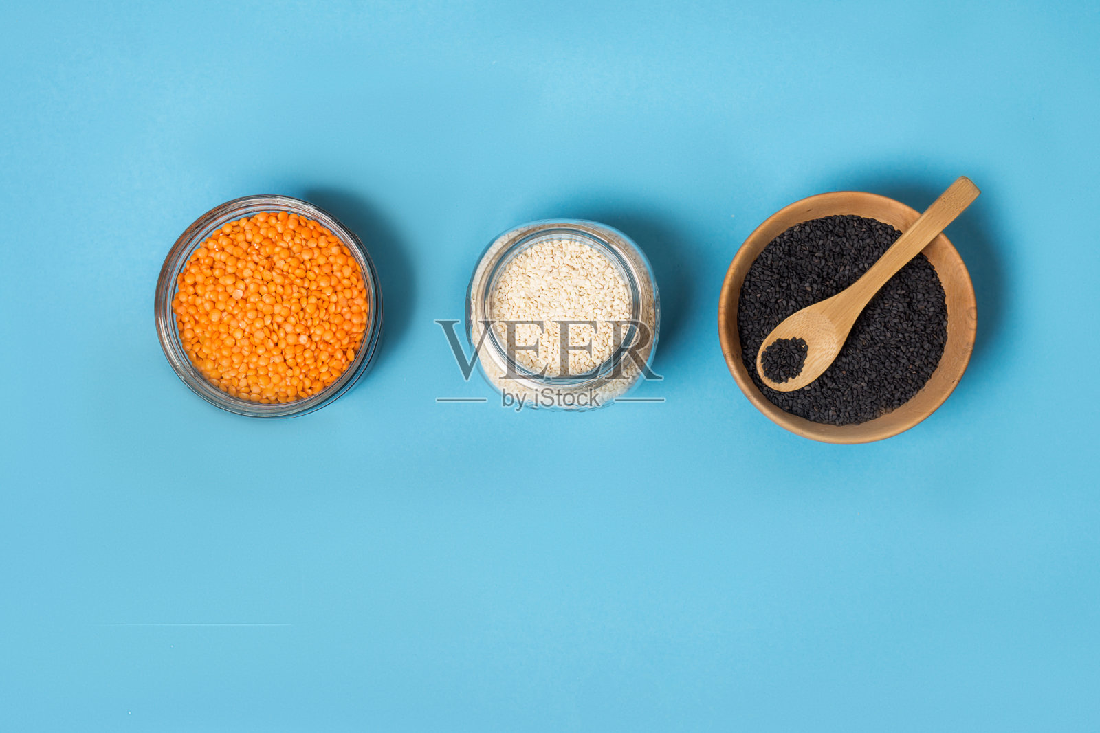 各种白芝麻籽和黑芝麻籽的桔小扁豆放在玻璃罐里的木盘上一个竹勺，俯视图。“零浪费”。照片摄影图片