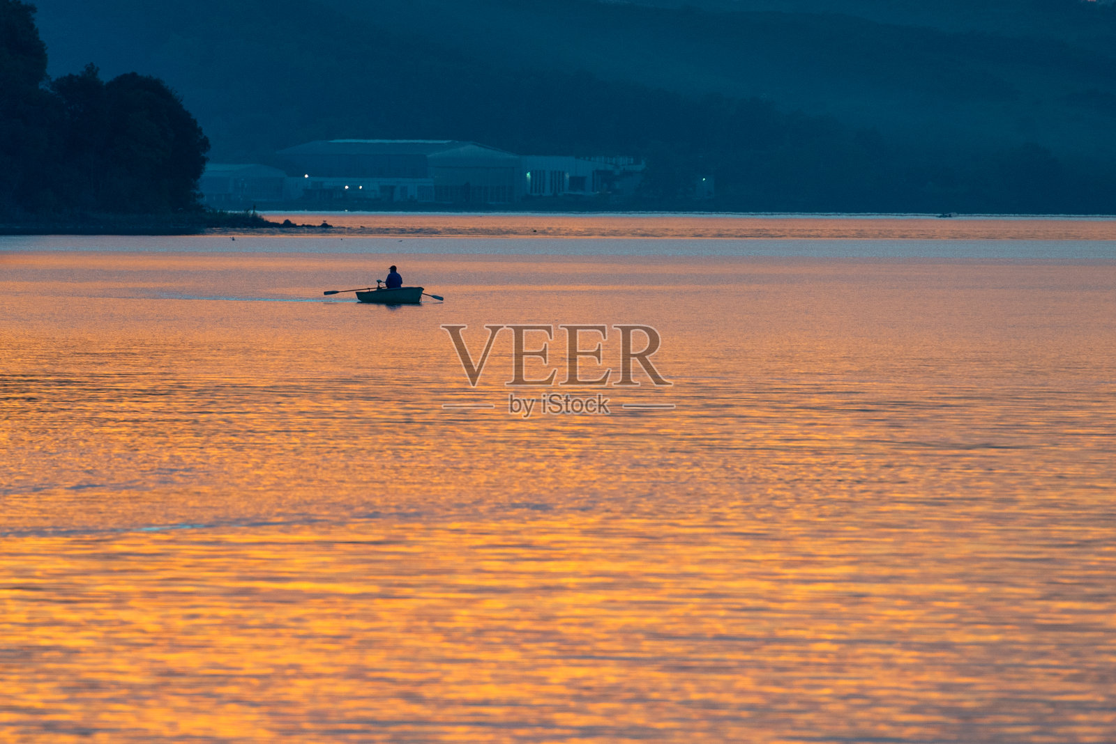 傍晚钓鱼湖上的渔夫船照片摄影图片