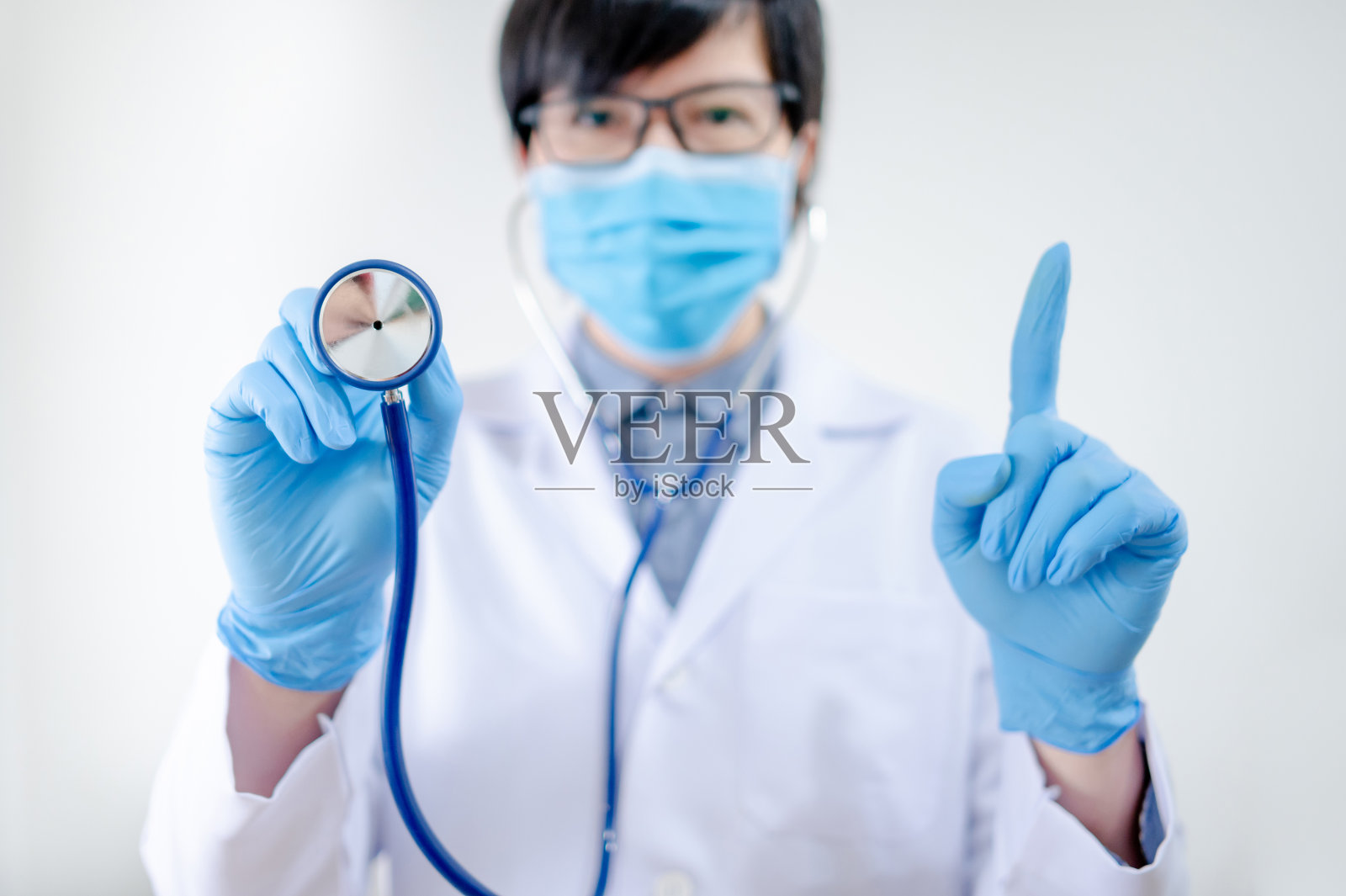 手持听诊器戴口罩的男医生照片摄影图片