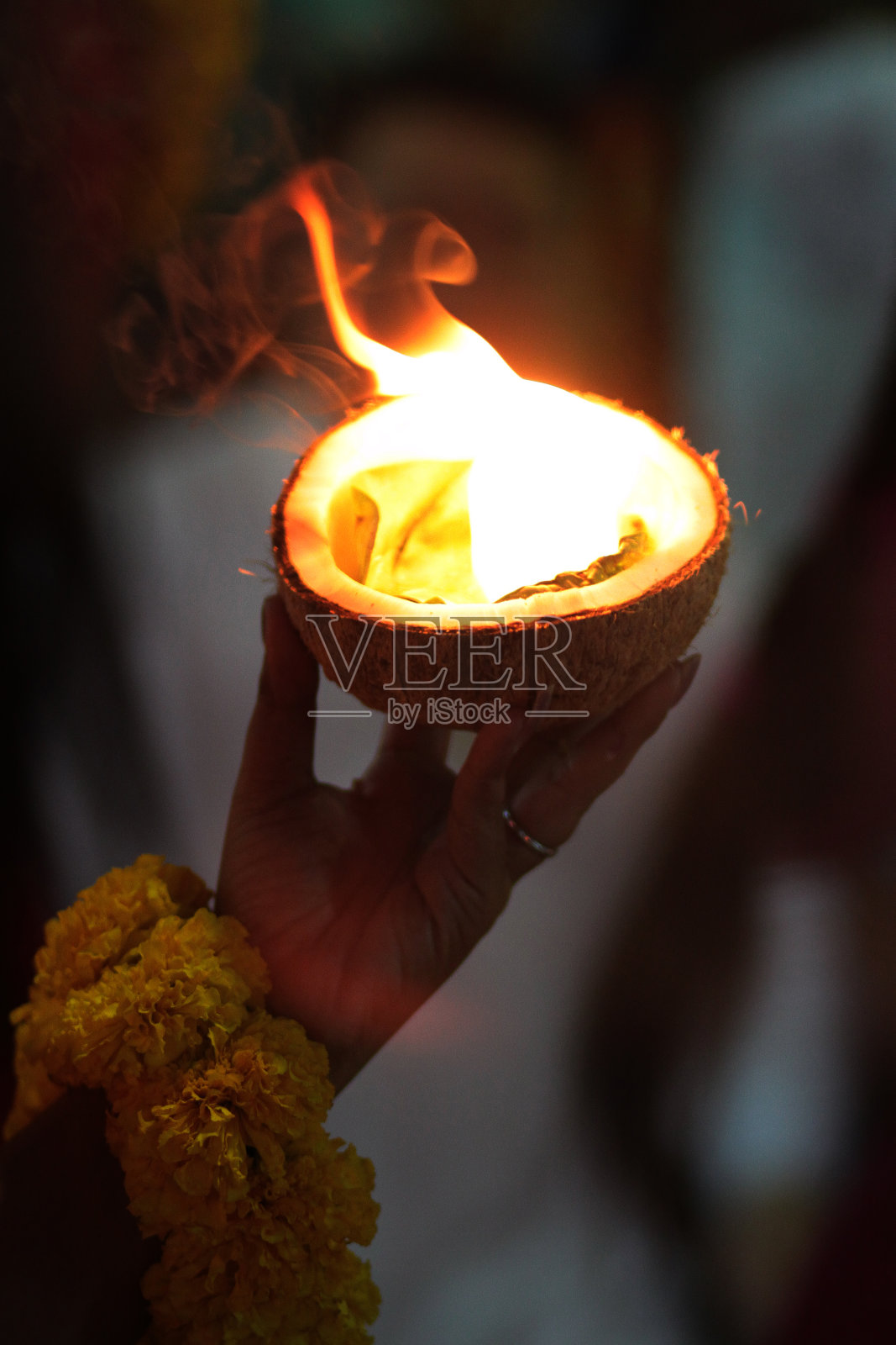 在泰国，一名女子手持椰子壳点燃篝火，表示对印度教诸神的信仰和崇拜照片摄影图片