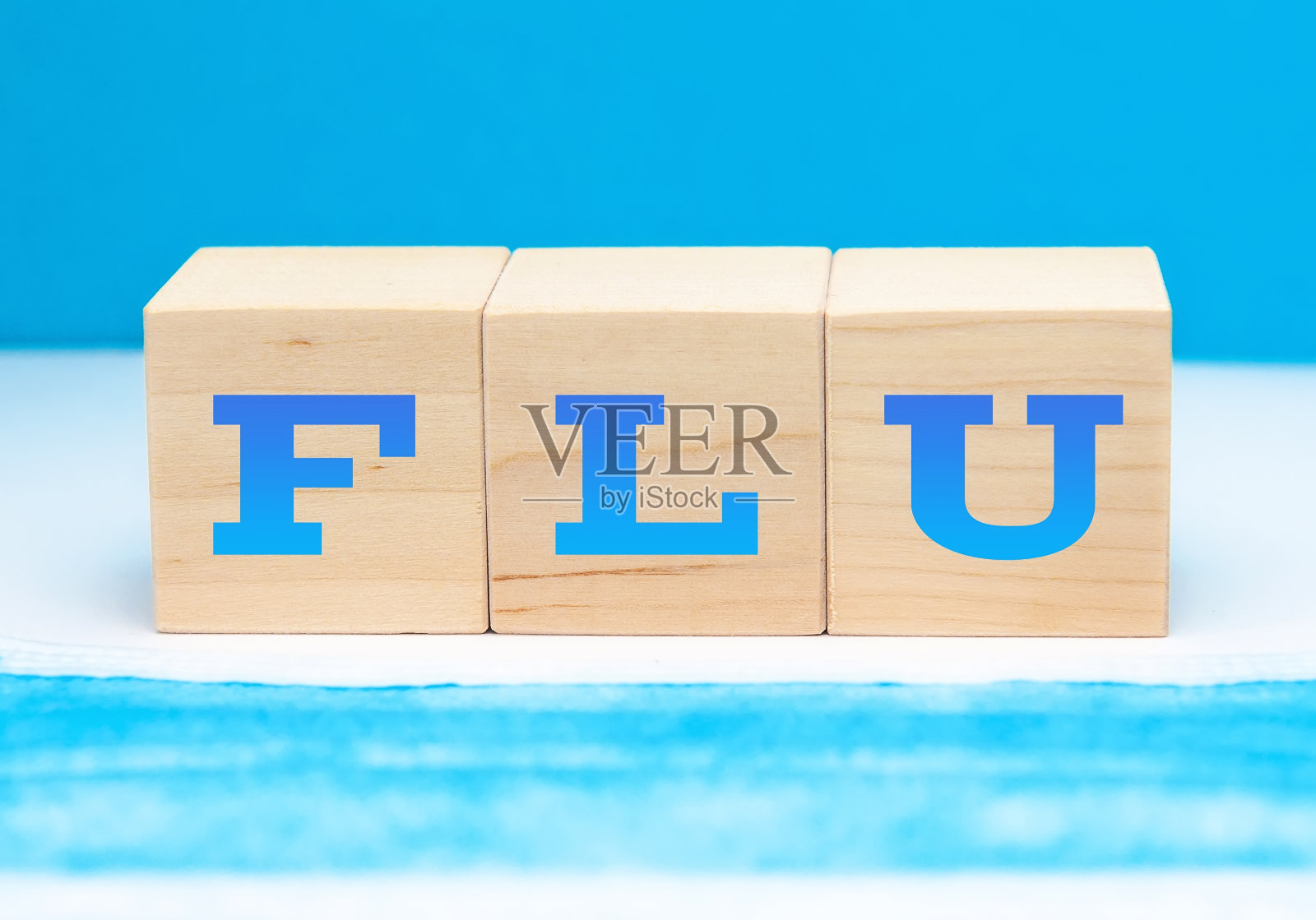 流感的概念。“蓝色”这个词位于一个医用口罩背景上的木立方体上。照片摄影图片