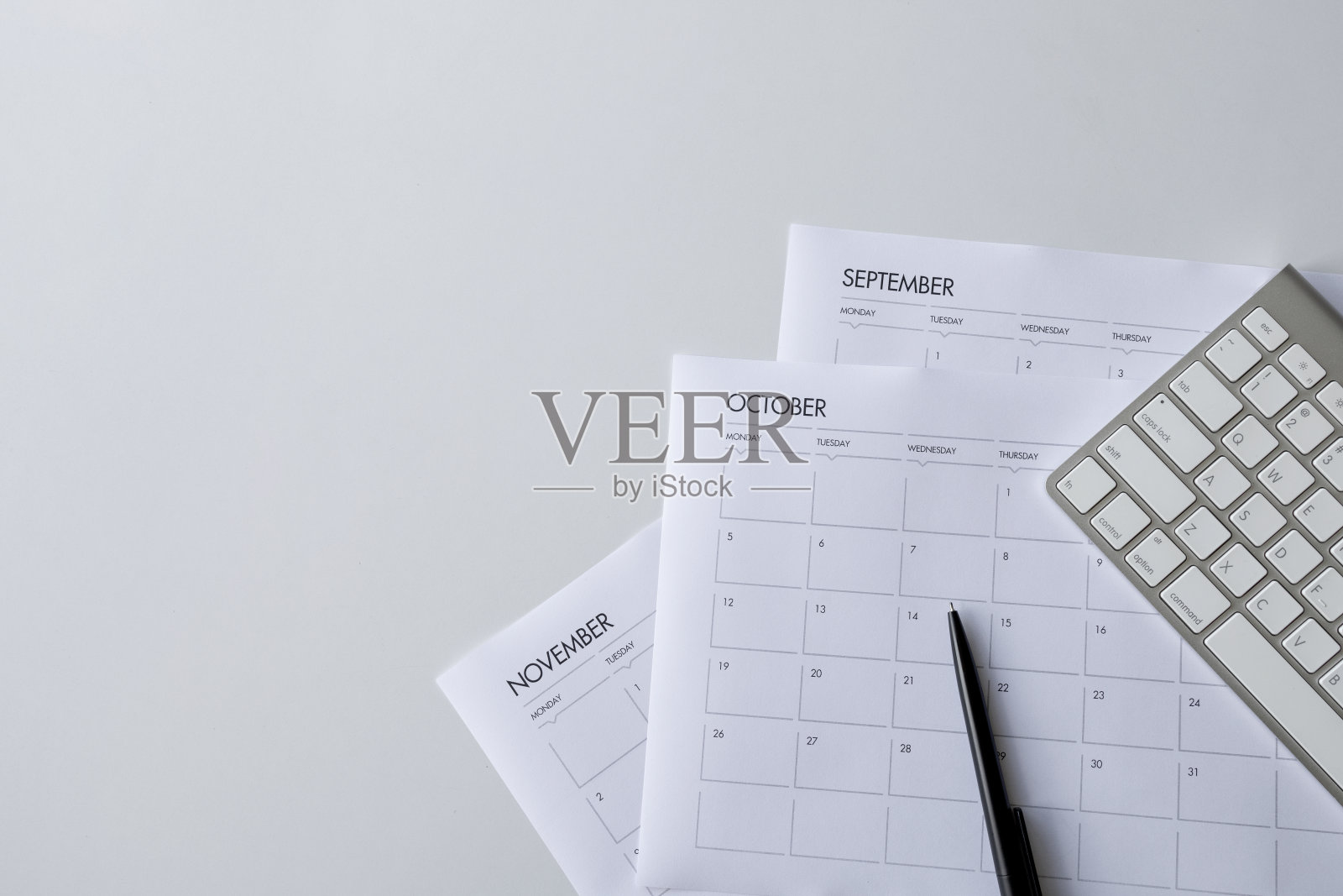 顶视图的办公桌工作空间与咖啡杯，键盘和工作时间表在白色桌子的背景。平躺照片摄影图片