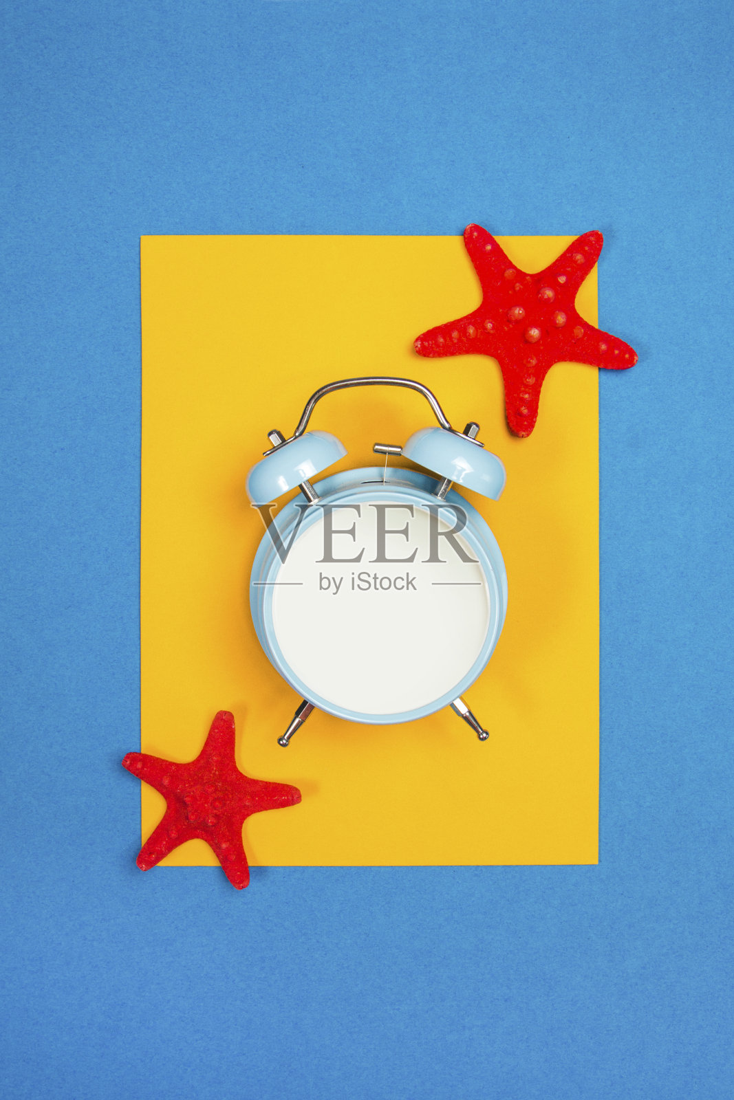 黄色和蓝色背景上有海星的蓝色闹钟照片摄影图片