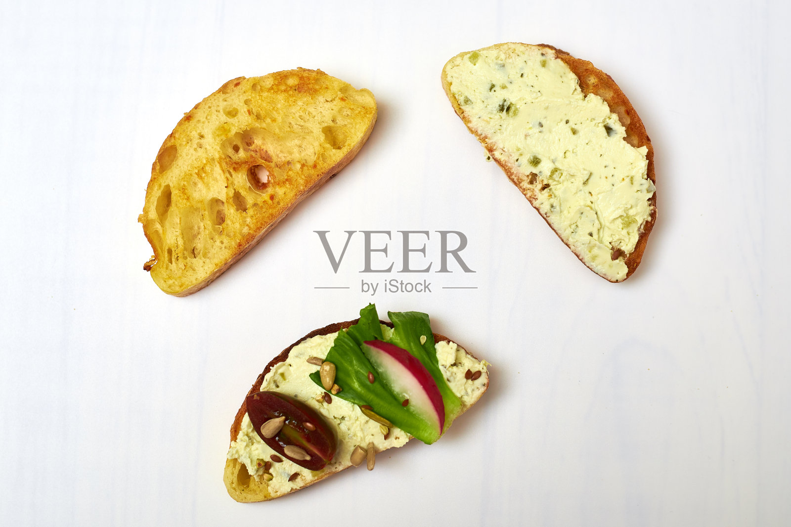 意大利脆皮意大利面包配奶油芝士和蔬菜放在白色盘子里。照片摄影图片