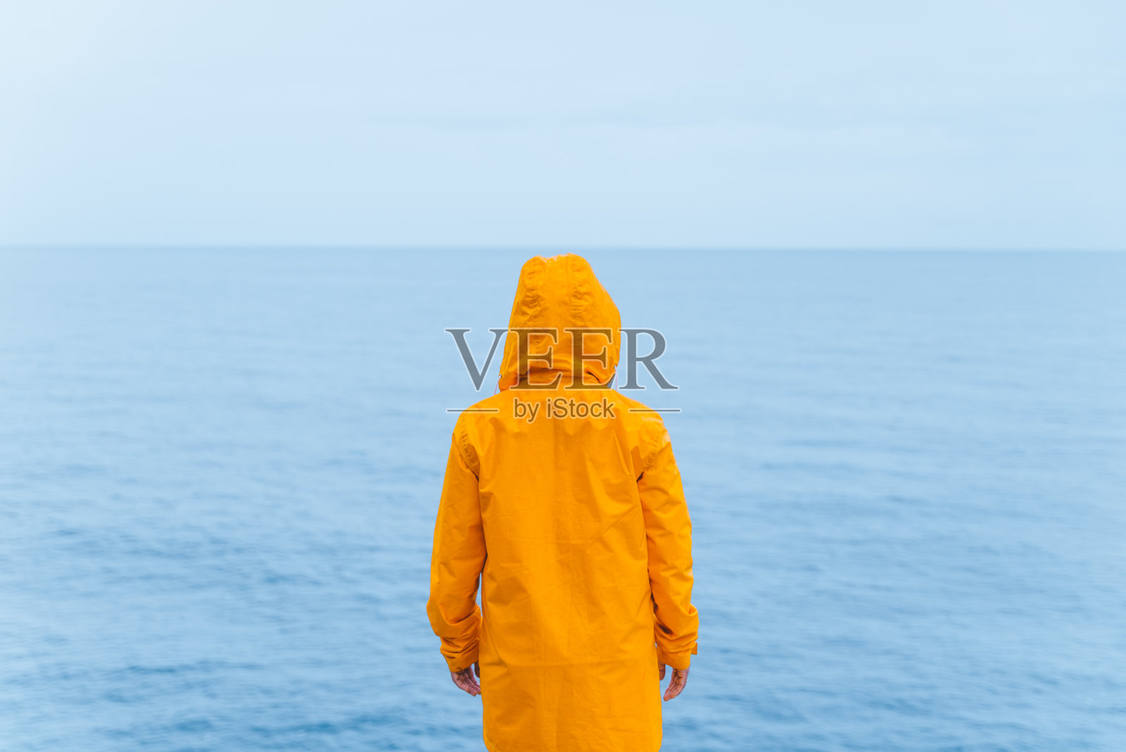 穿着黄色雨衣的女人在海边悬崖在暴风雨雨天的天气照片摄影图片