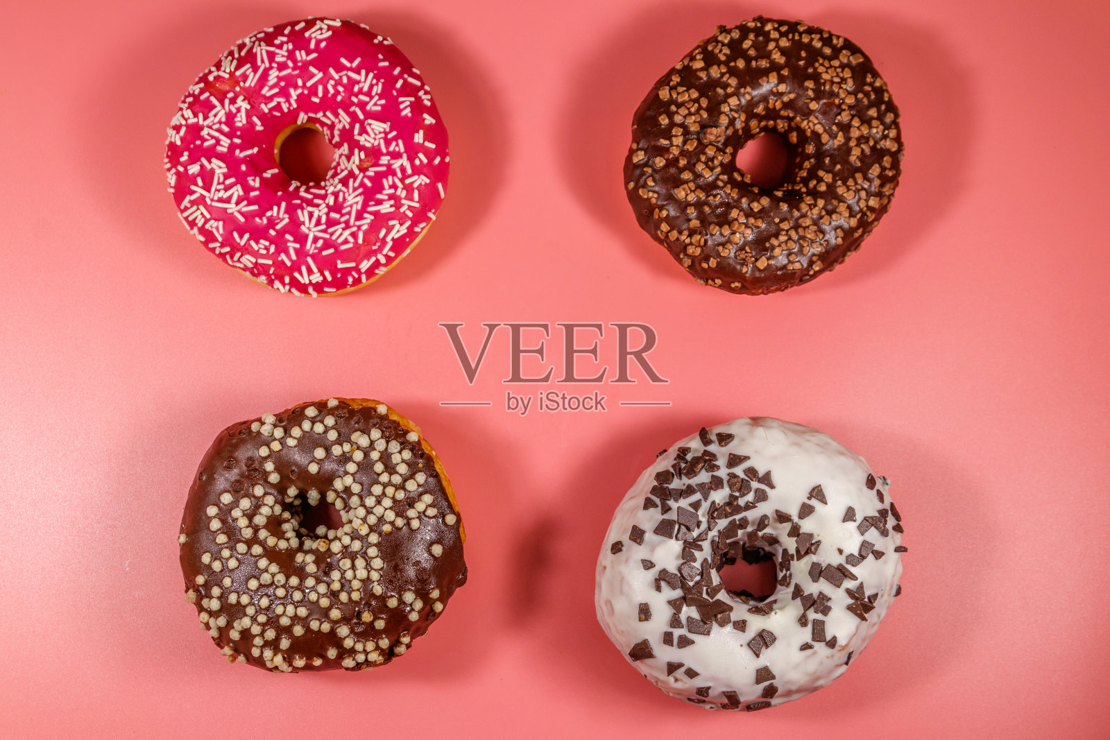 粉红色背景上的美味甜甜圈。俯视图照片摄影图片