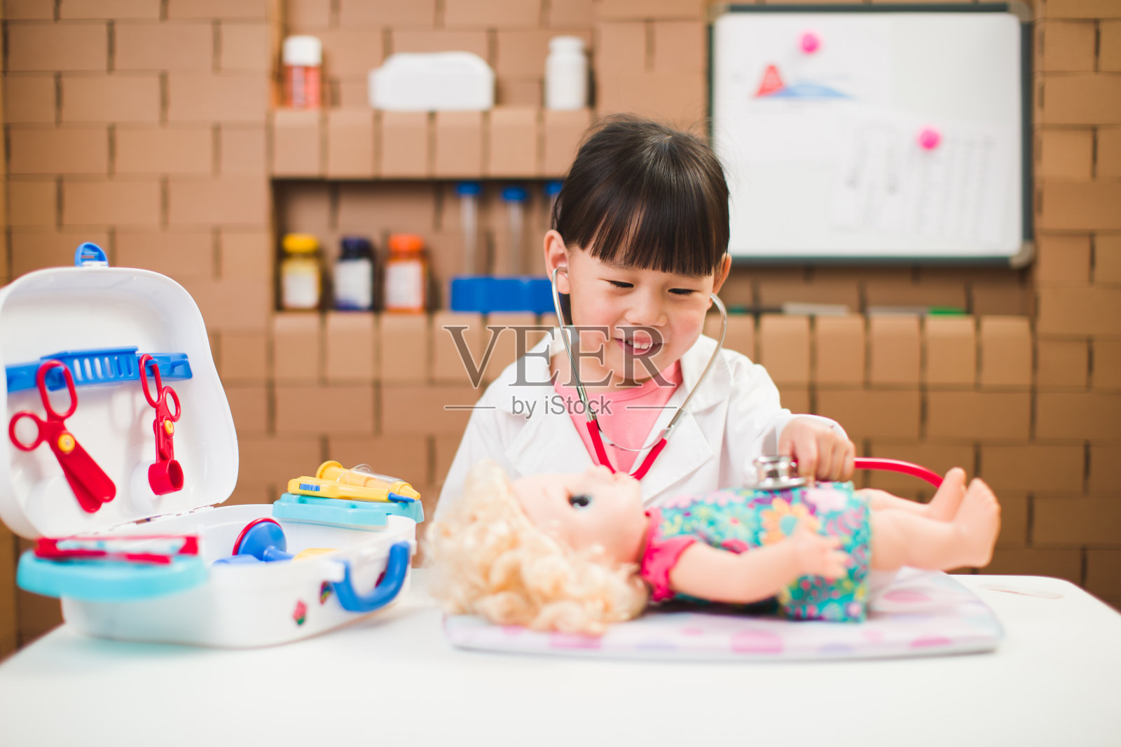 蹒跚学步的女孩在家里扮演医生的角色照片摄影图片