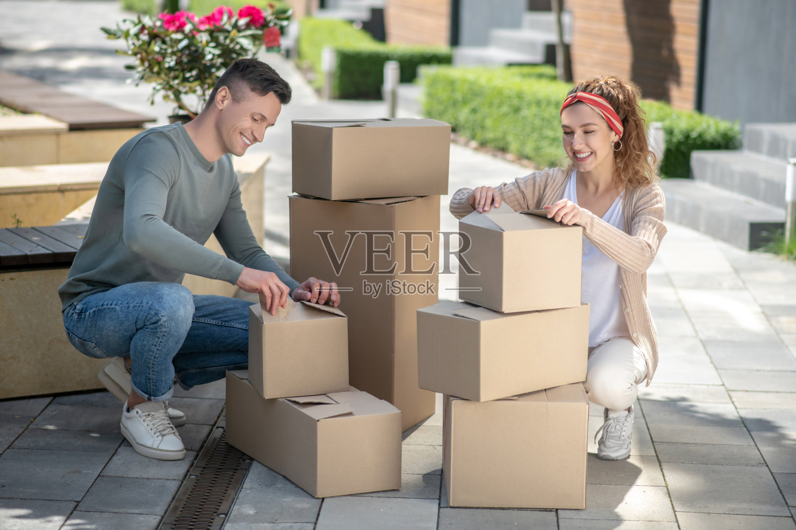 漂亮女人和她的丈夫坐在纸板旁照片摄影图片