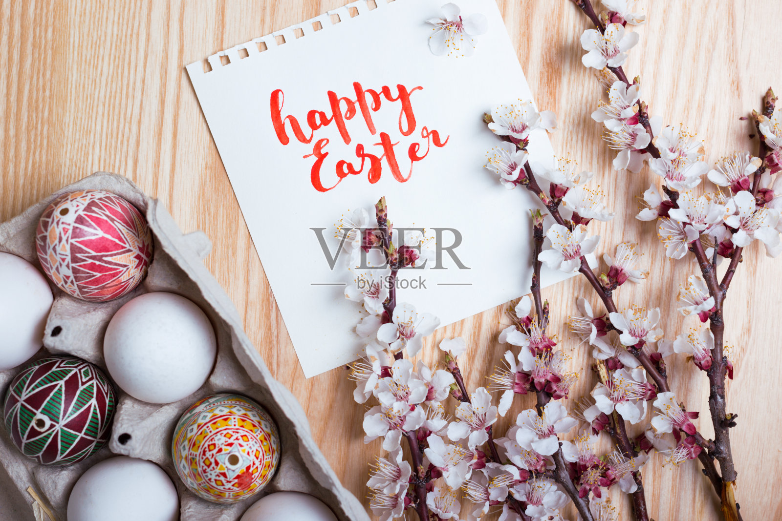 复活节快乐卡。盒子里装着漂亮的复活节彩蛋，皮桑卡手工制作，还有盛开的杏树枝，在木制的背景上照片摄影图片