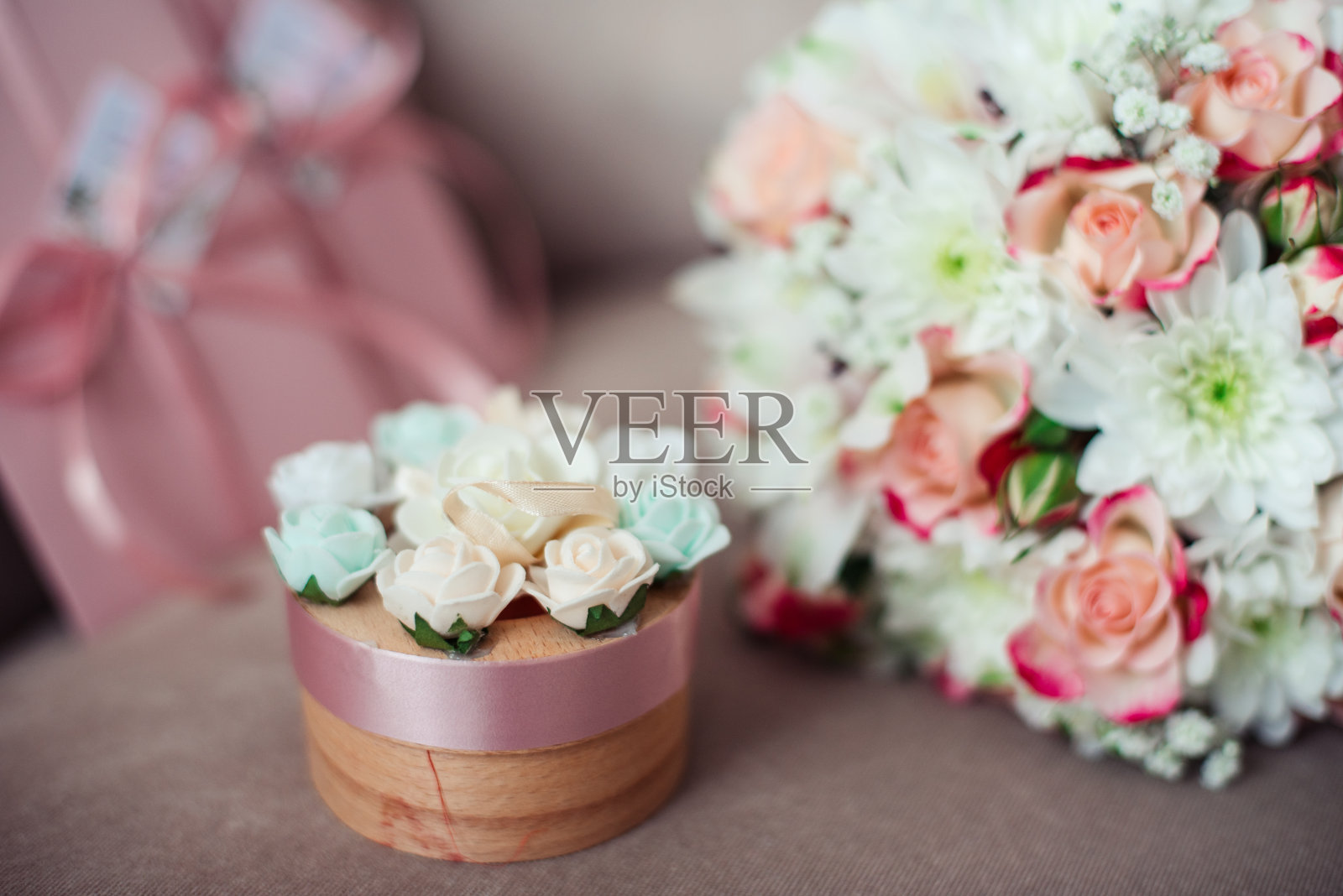 婚礼上一束粉红色玫瑰和白色菊花的特写，背景是粉红色的证书和一个盒子在一个粉状的沙发上照片摄影图片