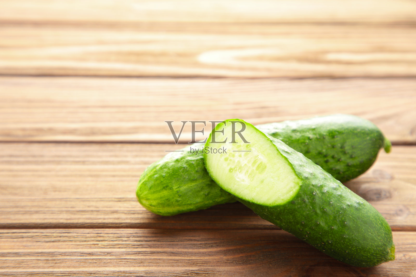 新鲜的黄瓜和切片在棕色的木背景上。照片摄影图片