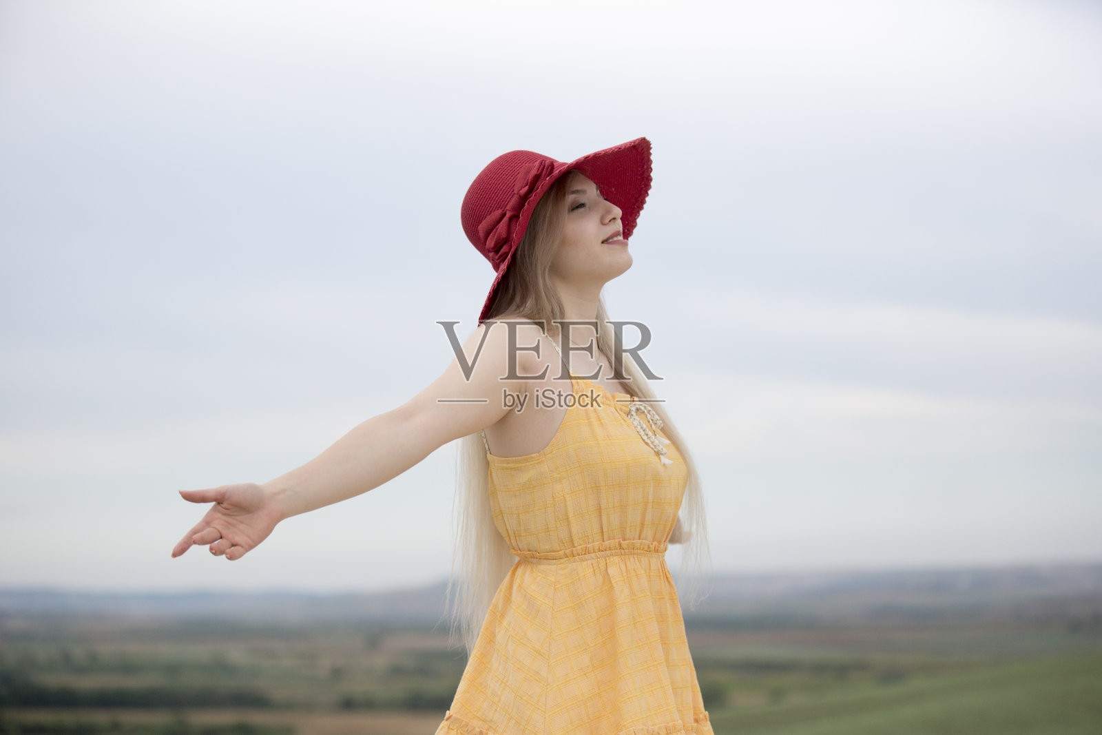 在一个阳光明媚的日子里，一个年轻女子在草地上伸出双手照片摄影图片