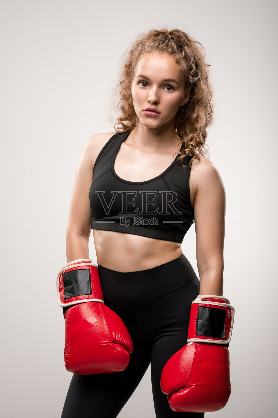金发女孩穿着黑色运动服戴着红色拳击手套站在镜头前照片摄影图片
