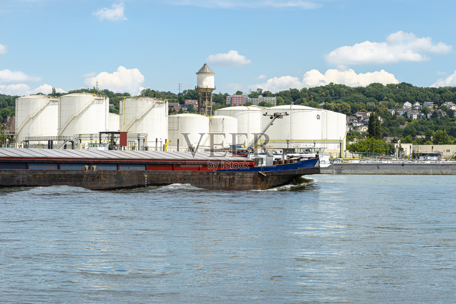 储存筒仓，燃料库的石油和汽油在河边在德国西部美丽的蓝天白云。可见煤炭驳船。照片摄影图片